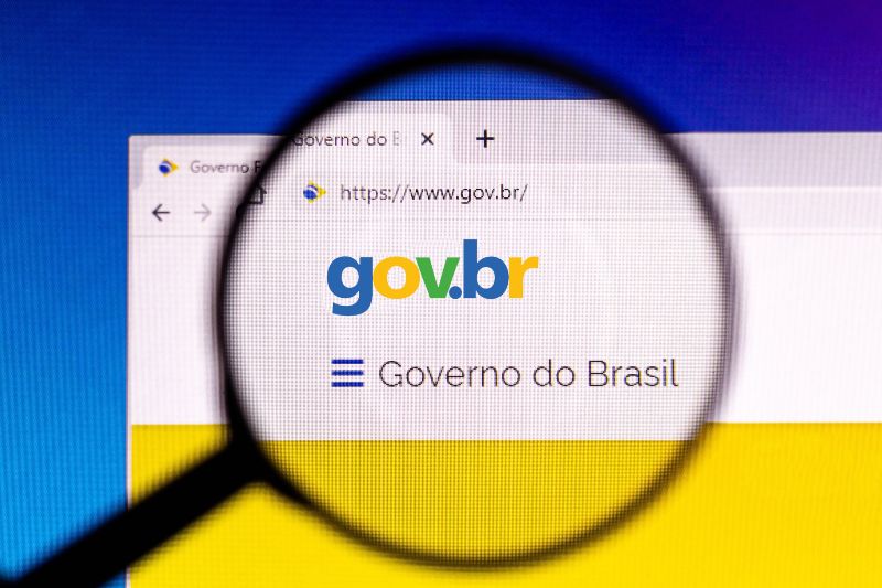 Foto de uma tela de computador com o navegador aberto no site gov.br e uma lupa de aumento sobre o texto 